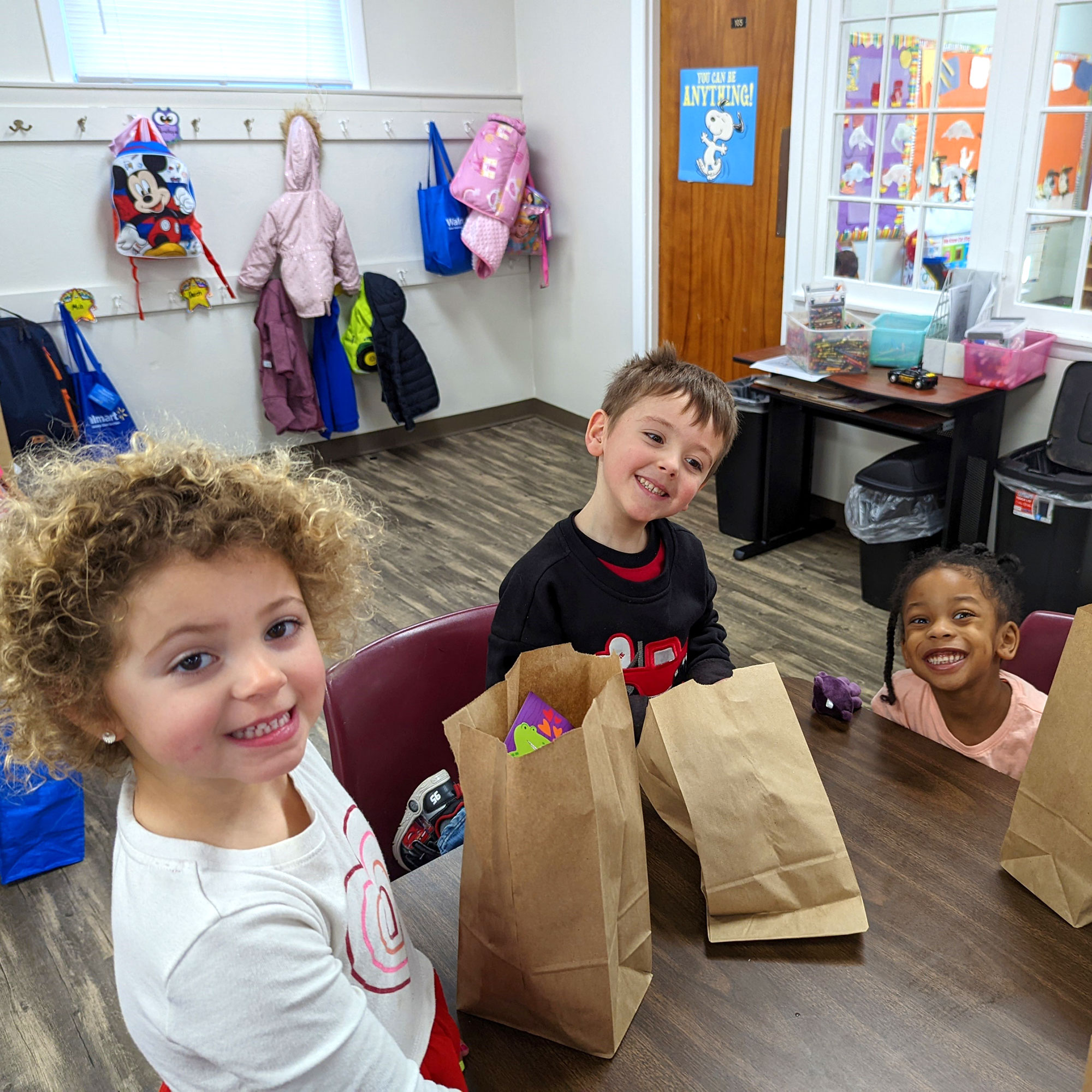 三个小孩检查他们的午餐在学校棕色袋。